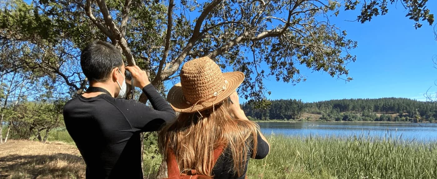 Pareja observando aves con binoculares frente al Lago Vichuquén